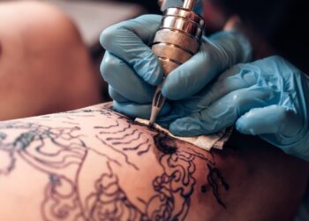 Closeup tattoo artist fill circuit tattoo in a professional salon. Leg with a pattern and black paint. Master works in black sterile gloves. SSUCv3H4sIAAAAAAAEAJ2RTW6EMAyF95V6B5Q1keIQAulVqi6Mk5lGZcgIwlTViLs3/FVZd8f77Eee7efrS1GwDidP7K14ripp3/fzFEeMPgwJi/LgzvoYRo/9Cle2bBU2RYzz5Kb1FwcijO6aend4+M933nddnIWtmBypxFiZsWnuNnaipfy3c//4OEfBqxvoZwucDTK63uE+yJGRXcAQaCQusAaupCLeSSKuldYXaMFo6M6XGRiLjTYth1qkZtAV7yrb8ooQO2yMEWj/mgXY2kgUXDa14UpJ4i0mh9ItkDRCqRa3/Hto9vUd3XjLl/zw1oVM42x9yPb9CIT9aqiyGe+jJz9cM1uIn27Mb5eOH24ZGELcdnKsmNl03FVCBUJrAarRtRRKViblXX4BnITL3lQCAAA=